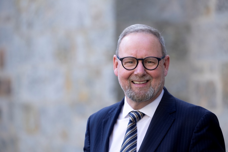 Image of Board Member Alasdair Hay standing outside of an office building.